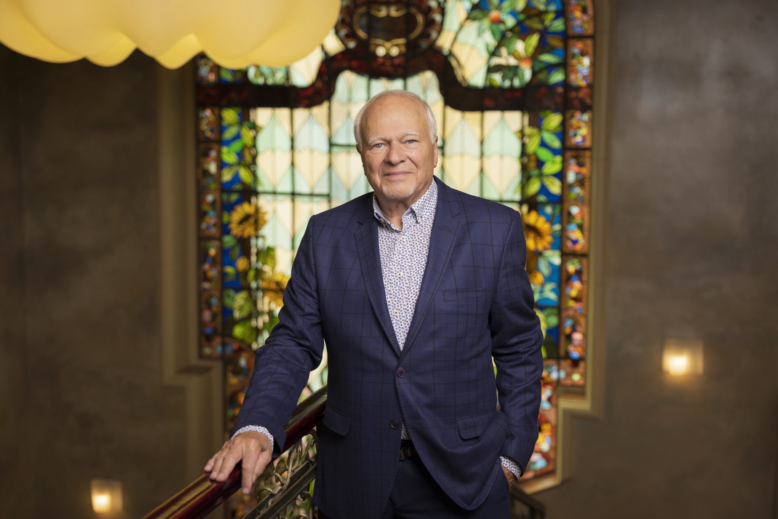 Businessman and art collector András Szabó standing before the Art Nouveau stained glass window at ResoArt Villa, owner of the ResoArt Collection