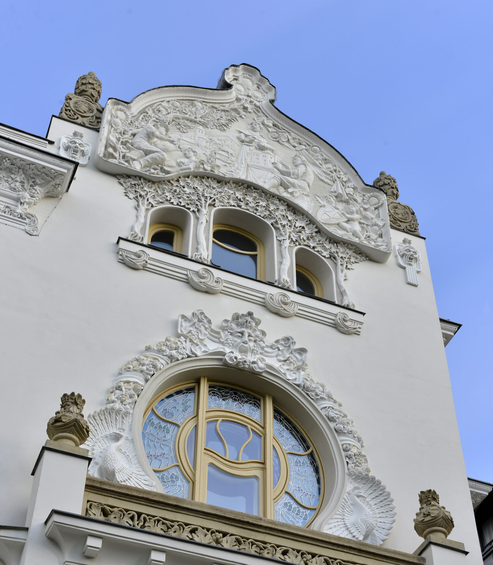 The Art Nouveau gable and ornate windows of the Kőrössy Villa on Városligeti Fasor, Budapest, under a clear blue sky.